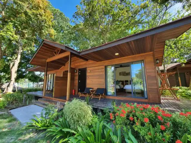 Modern wooden beach chalet at Borneo Divers Mabul Resort, surrounded by lush gardens and offering a luxurious stay for a Sipadan scuba diving getaway.