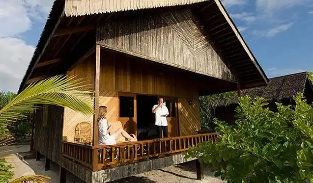 Couple relaxing on the veranda of a traditional-style Beach Villa at the 5-star Pom Pom Island Resort, a private island paradise near Sipadan.