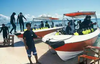 Scuba divers preparing for an adventure on dive boats beached at Borneo Divers Mabul Resort, ready to explore the world-class sites near Sipadan.
