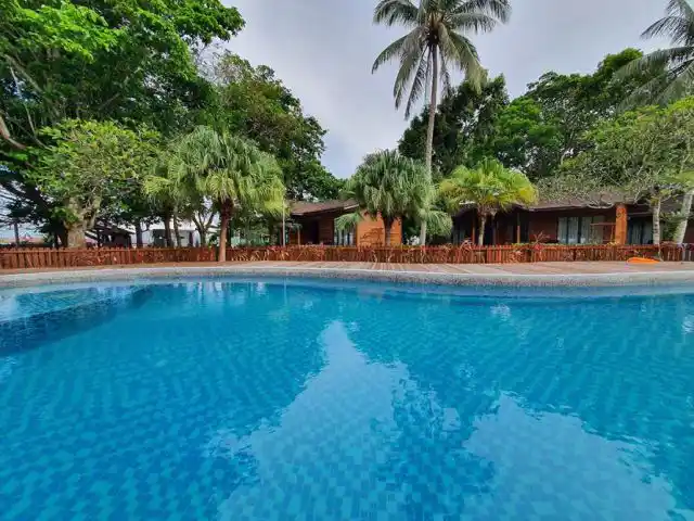 Inviting view from the swimming pool looking towards the poolside chalets nestled amongst lush tropical greenery at Borneo Divers Mabul Resort.