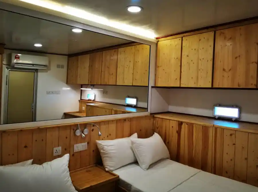 Comfortable and compact twin cabin on the MV Celebes Explorer 9 (CE9) liveaboard, featuring warm wood paneling and plenty of storage for a Sipadan dive trip.