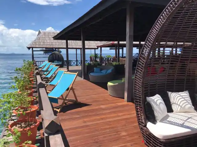 Relaxing open-air jetty lounge at Borneo Divers Mabul Resort, with comfortable seating perfect for enjoying the sea breeze after a day of diving.
