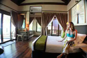 Guest relaxing in the spacious and elegant bedroom of a Beach Chalet at Mataking Island, a luxury resort perfect for a honeymoon.