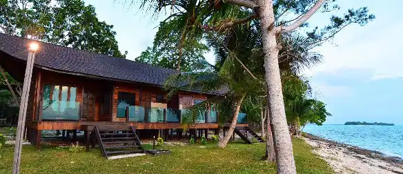 Beachfront view of a luxury wooden chalet at Mataking Island Resort, perfectly situated on the sand with the sea just steps away.
