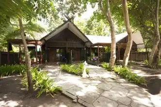 Pathway leading to a Deluxe Room building at Mataking Island Resort, beautifully integrated into the lush tropical gardens and trees.