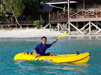 Guest enjoying a relaxing paddle in a kayak on the calm, turquoise sea in front of the Mataking Island Resort.