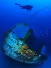 Scuba diver exploring the purpose-sunk shipwreck at Mataking Island, now a thriving artificial reef and popular dive site.