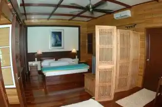 Cozy and luxurious bedroom in the Bougainvilla chalet at Mabul Water Bungalows, featuring warm wood paneling and elegant furnishings.