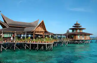 Impressive main building and restaurant of Mabul Water Bungalows, showcasing traditional architecture built on stilts over the clear turquoise sea.