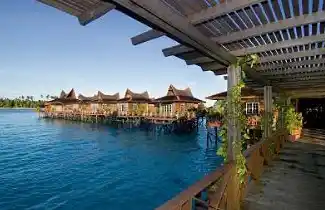 View along the covered walkway connecting the award-winning overwater chalets at Mabul Water Bungalows, a 5-star honeymoon resort.