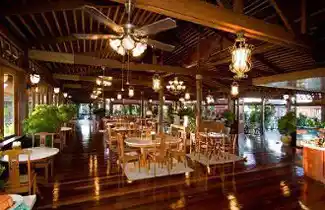 Elegant open-air dining hall at Mabul Water Bungalows illuminated with warm lights in the evening, offering a luxurious atmosphere for guests.