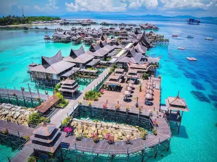 Spectacular aerial drone view of the entire Mabul Water Bungalows resort, its intricate network of jetties, and the surrounding turquoise Celebes Sea.