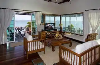 Relaxing lounge area in a luxury suite at Mabul Water Bungalows, with panoramic windows and a private deck overlooking the ocean.