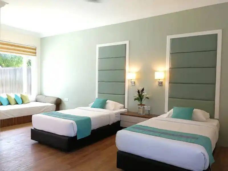 Bright and spacious interior of a Premium Room at Mataking Island Resort, featuring twin beds and a comfortable daybed by the window.