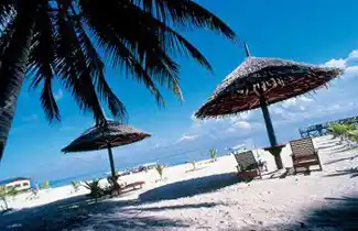 Relaxing on the white sand beach under a thatched umbrella at Sipadan-Mabul Resort, the perfect tropical holiday getaway on Mabul Island.