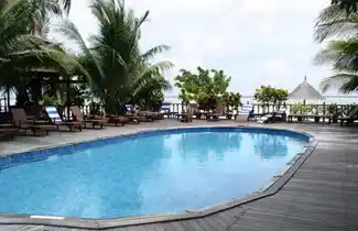 Refreshing swimming pool at Sipadan-Mabul Resort, surrounded by a wooden sundeck and palm trees with a view of the sea.