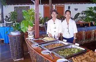 Friendly staff presenting the delicious buffet spread at the Sipadan Water Village restaurant, served from a unique boat-shaped counter.