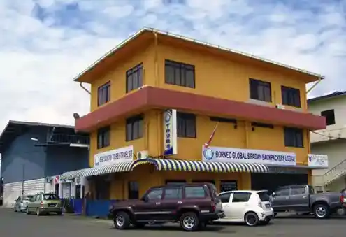 Bright yellow building of Borneo Global Sipadan Backpackers Lodge in Semporna town, a licensed dive operator offering budget stays and guaranteed Sipadan permits.