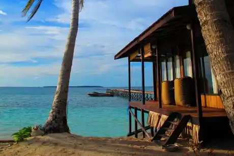 Idyllic beachfront bungalow at Derawan Dive Lodge in East Kalimantan, offering a private island escape with stunning views of the jetty and turquoise sea.
