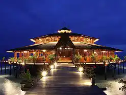 Spectacular over-the-water restaurant at Lankayan Island Resort, beautifully illuminated against the deep blue twilight sky for a magical dining experience.