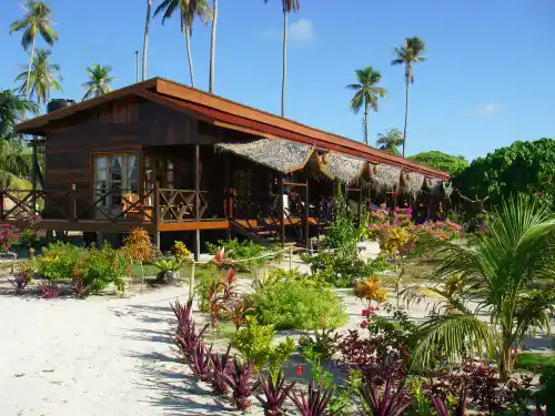 Beautiful wooden chalet at Mabul Beach Resort, nestled on the sand among lush tropical gardens and palm trees on Mabul Island.