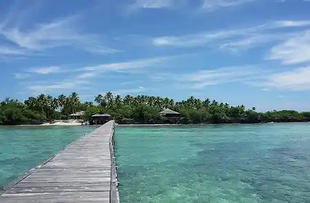 Walking along the wooden jetty towards the private Nunukan Island Resort, a PADI dive resort surrounded by turquoise water in East Kalimantan.