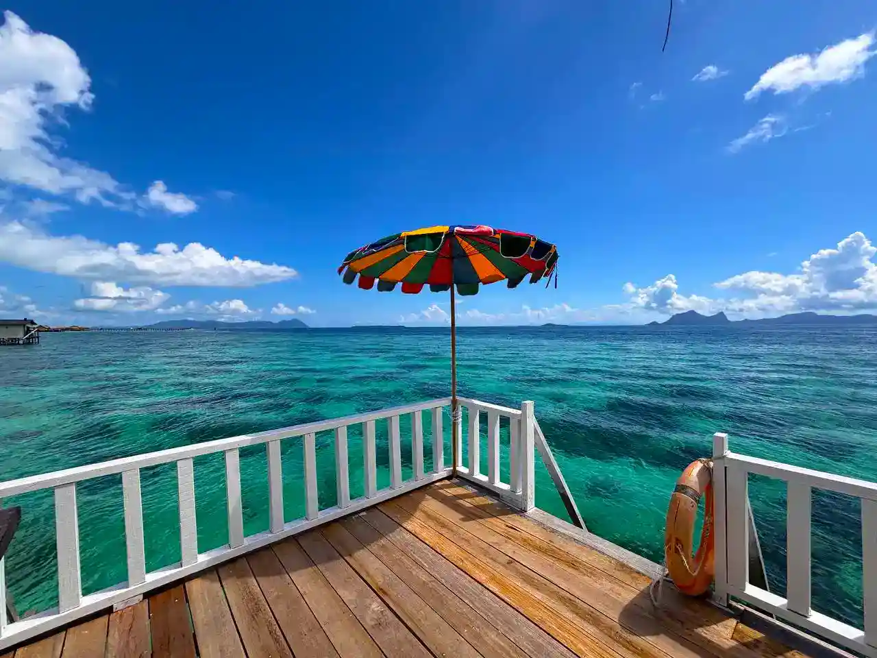 Stunning ocean view from a private balcony at Blue Ocean Resort, with a colorful umbrella providing shade to enjoy the turquoise sea and distant islands.