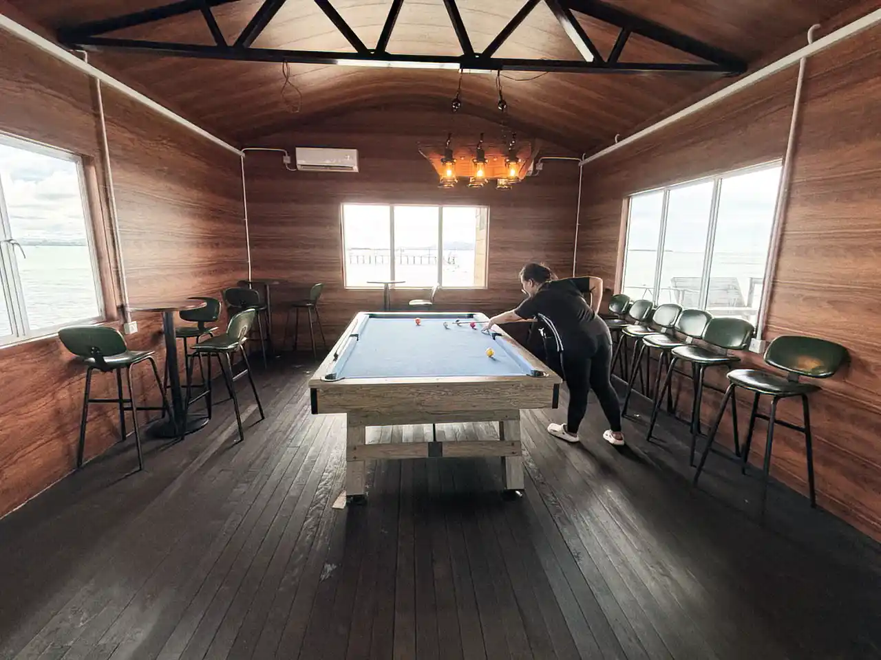 Guest enjoying a game of pool in the billiard and snooker room at Crystal Resort, with beautiful sea views from the windows.