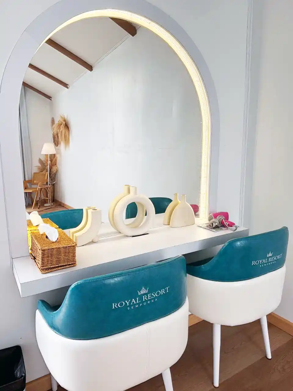 Chic vanity area at Royal Resort Semporna, with a stylish arched mirror and custom-branded chairs adding to the room's modern decor.