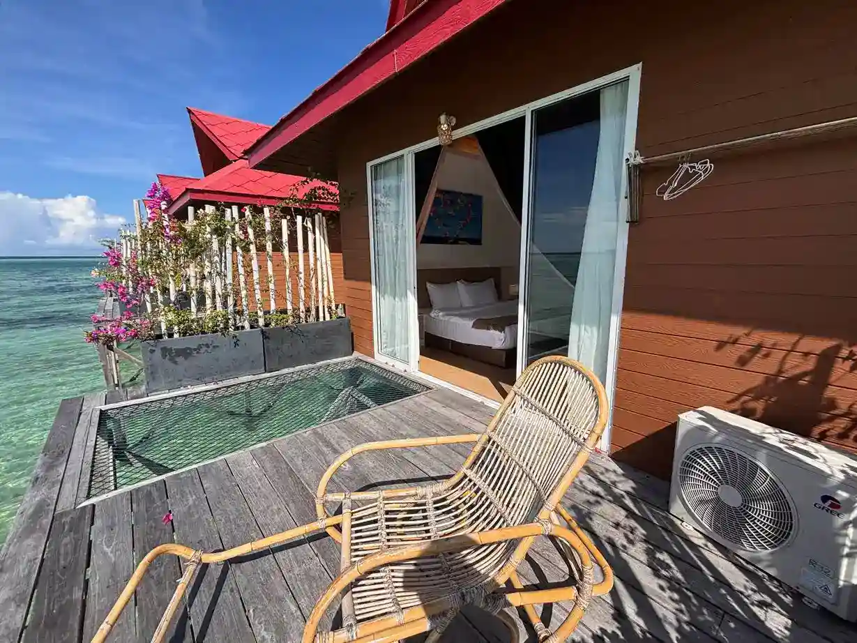 Private wooden balcony at Sand Bay Resort with a relaxing rocking chair and over-water net hammock, perfect for enjoying the seaviews.