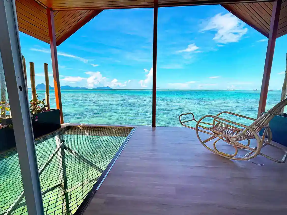 Private balcony at Sand Bay Resort with an over-water net hammock and rocking chair, offering incredible views of the Tun Sakaran Marine Park.