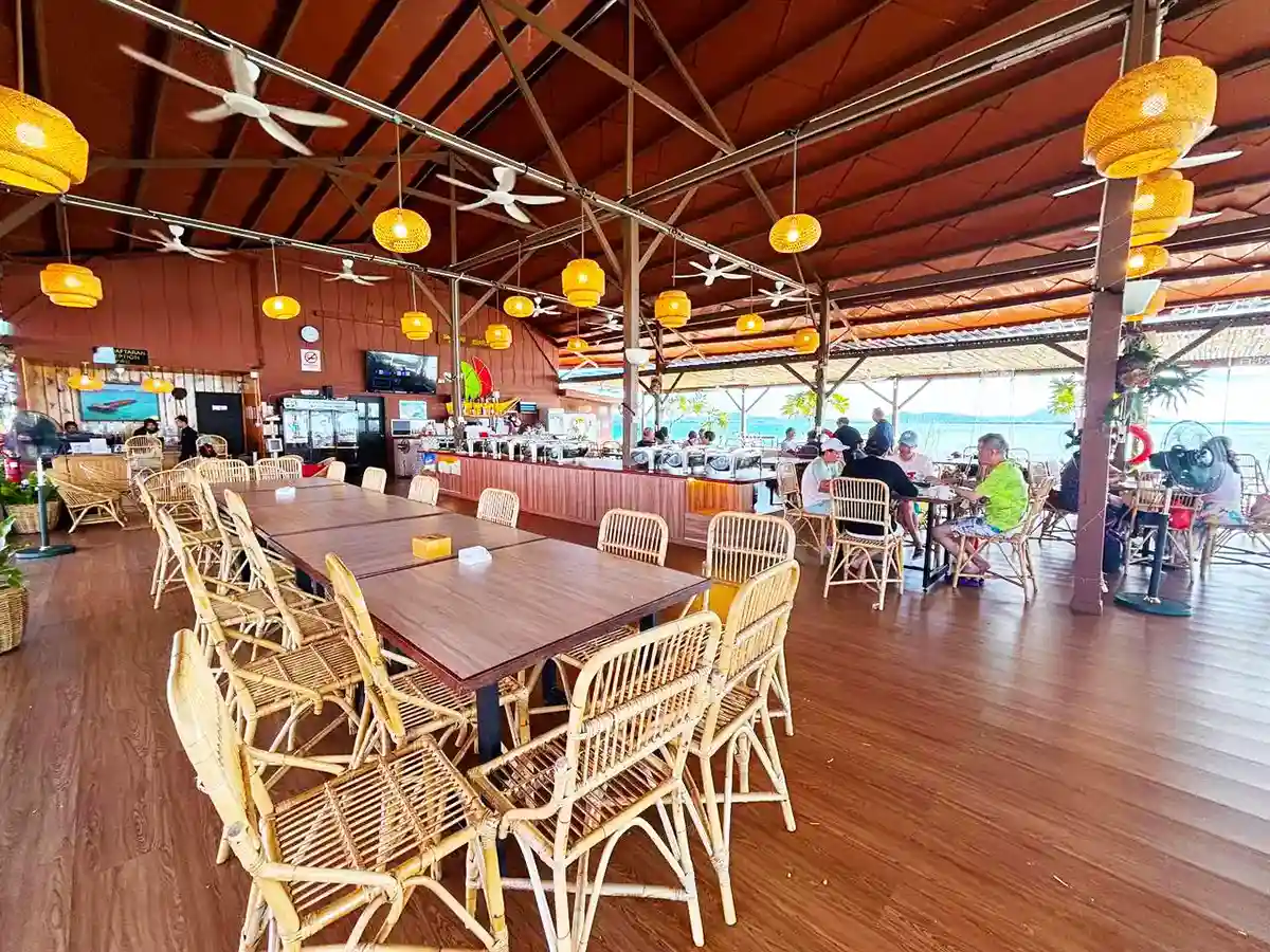 Spacious open-air restaurant at Sand Bay Resort, with wicker furniture and panoramic sea views for a casual tropical dining experience.