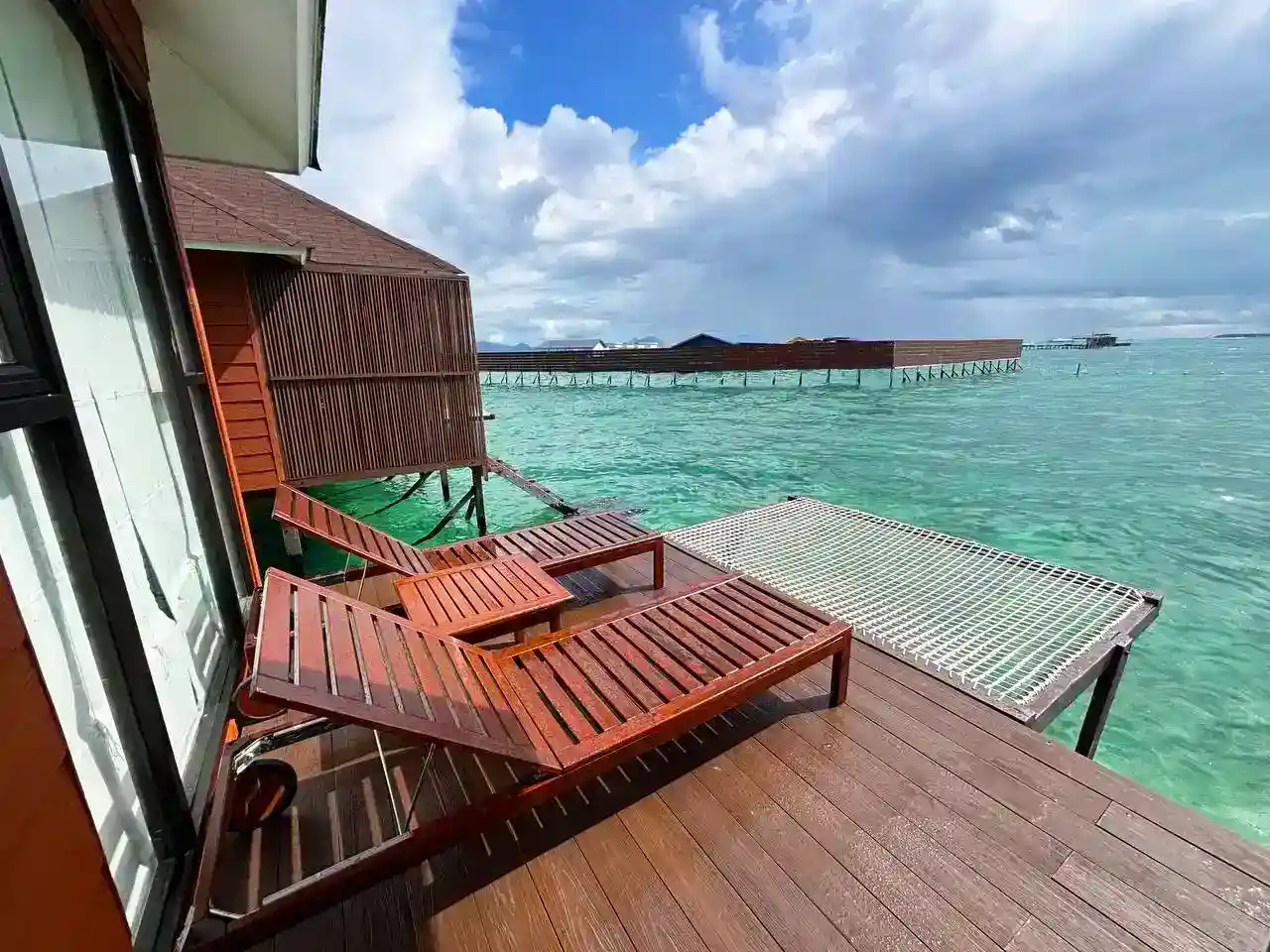 Private wooden sundeck at Sea Star Resort, featuring lounge chairs and an over-water net hammock for relaxing and enjoying the view.