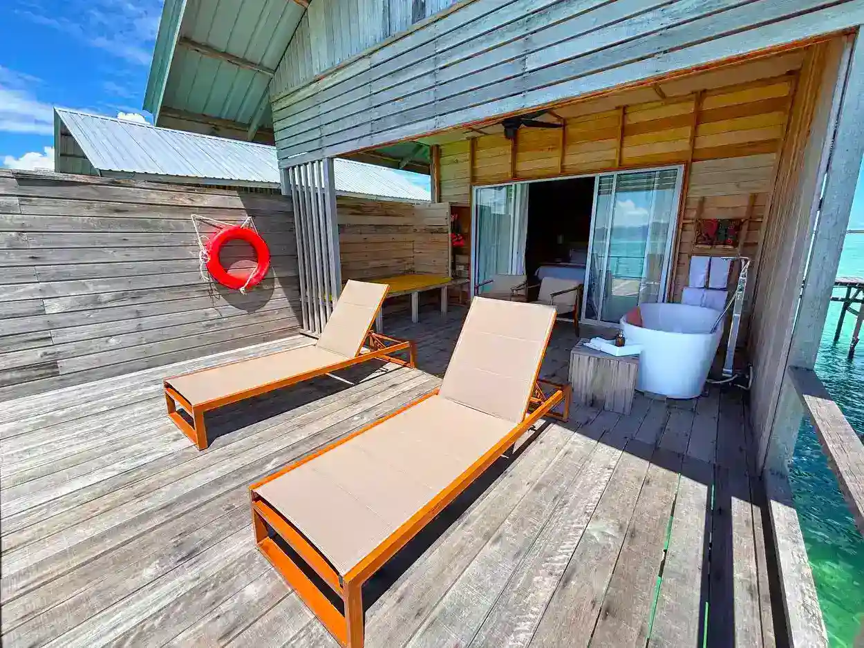 Expansive private wooden deck at Sisipan Island Resort, featuring sun loungers and a luxurious outdoor bathtub for ultimate relaxation over the water.