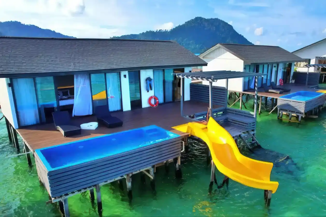 Fun and luxurious overwater chalet at Sky Resort Timbun Mata, featuring a private plunge pool and a personal yellow water slide into the sea.