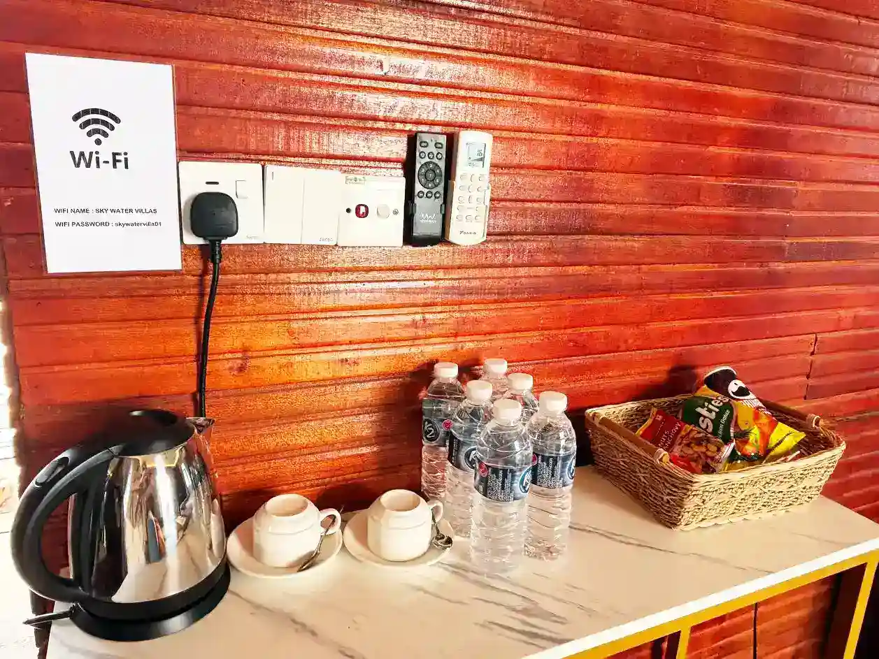 Complimentary in-room amenities at Sky Water Villas, including drinking water, snacks, a kettle, and a sign with the Wi-Fi password.