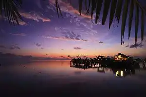 The sunsets here are truly spectacular every evening. Spectacular purple and orange sunset over a Sipadan water village resort, with lights from the jetty reflecting on the calm sea.